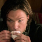 Sam drinks tea from a tiny teacup.